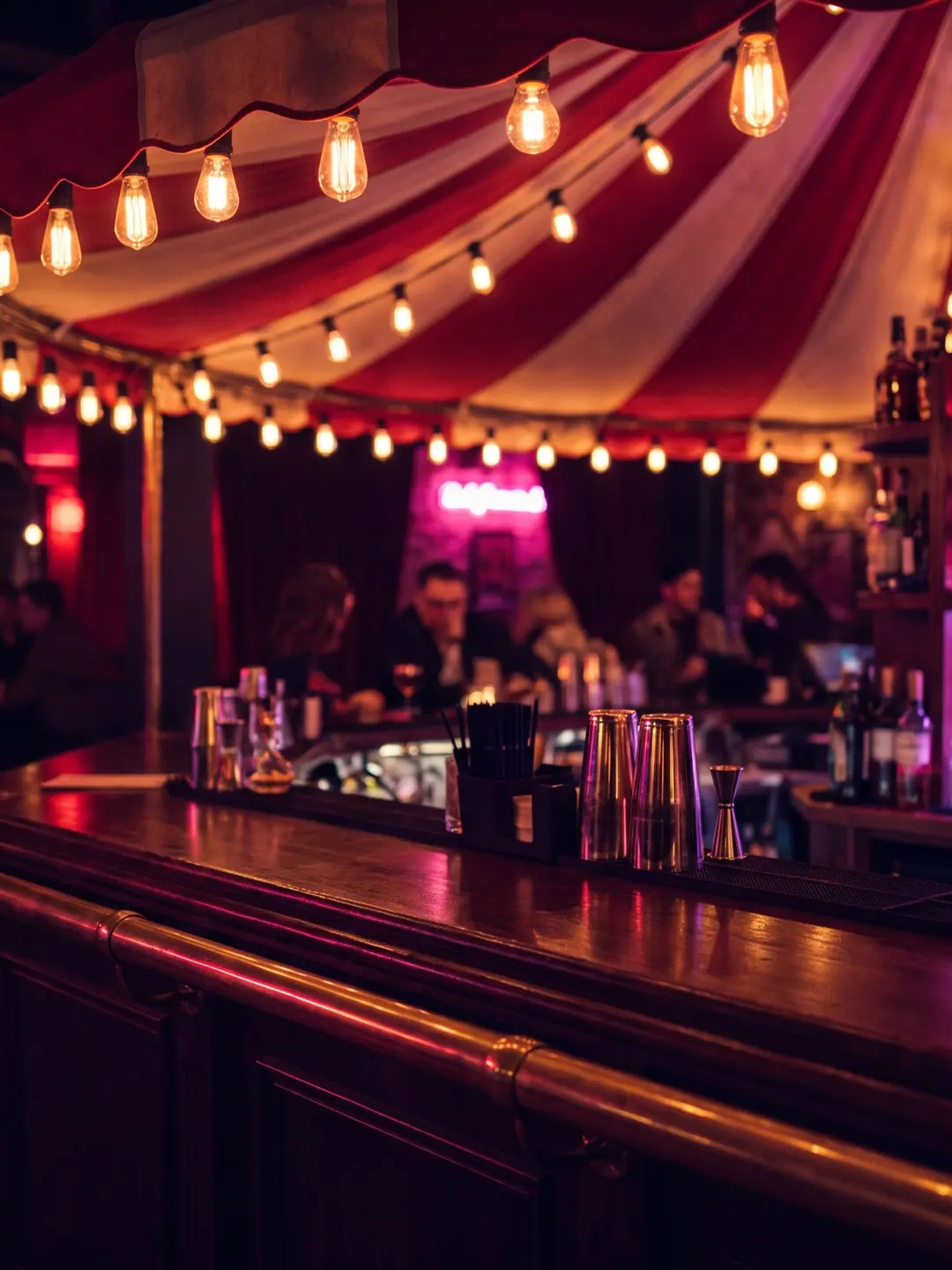 Le comptoir du Carrousel sous la marquise rayée, bouteilles rétroéclairées et ampoules dorées